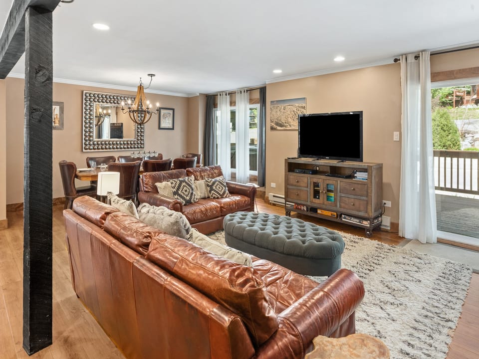 The beautifully appointed living room will make you feel right at home. - Bright room, large windows, brown couches.