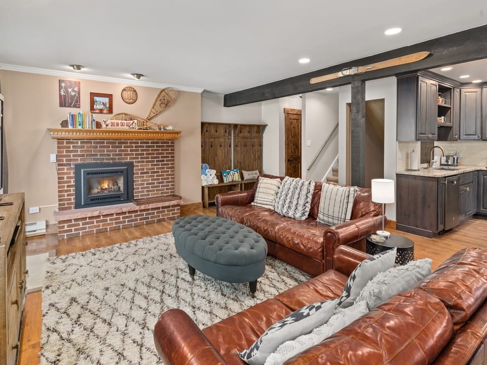 Warm up your toes next to the gas fireplace after a cold day in Steamboat! - Fireplace, brown couches, grey ottoman, white rug.
