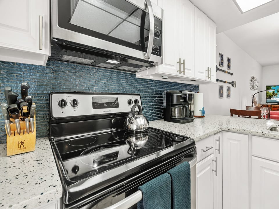 Cook delicious meals in this bright, fully-equipped kitchen featuring modern appliances, stunning granite countertops, and a gorgeous turquoise tile backsplash.