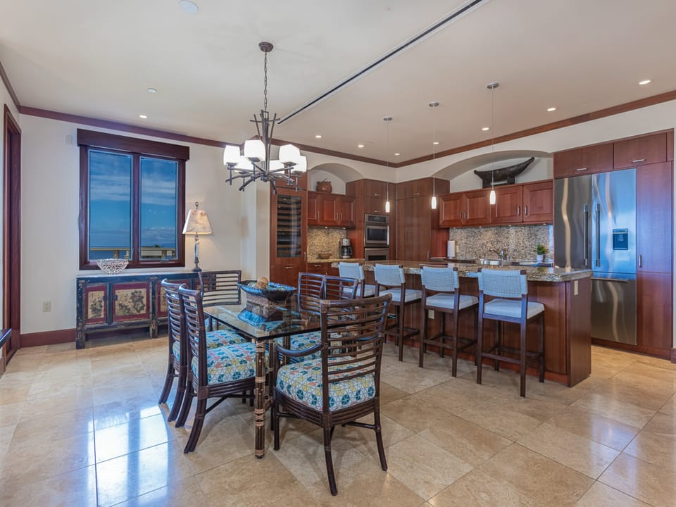 Your open-plan kitchen and dining area invites you to cook and gather together. Rich wood cabinetry, granite counters, stainless appliances, and ocean views through the windows create a warm, elegant space for memorable meals.