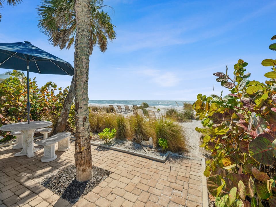 Your private beachfront patio features tropical landscaping, shaded dining, and direct access to pristine sandy shores.