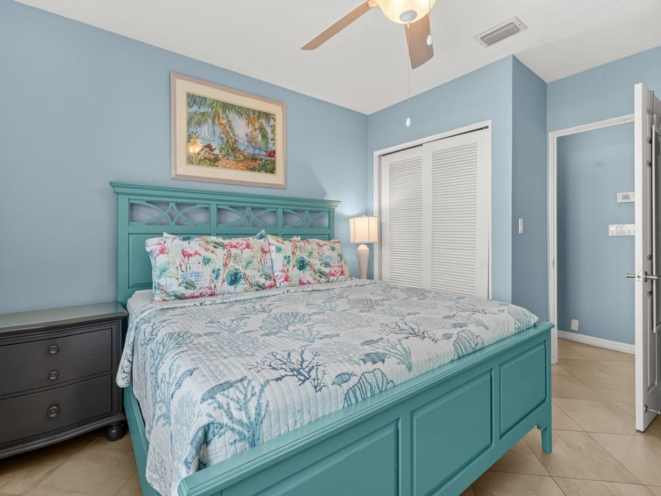 Drift off in your coastal-themed bedroom with turquoise bed frame and tropical linens under a gentle ceiling fan.