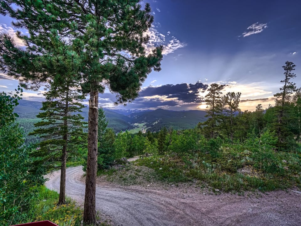 The sun is setting over a dirt road in the mountains.