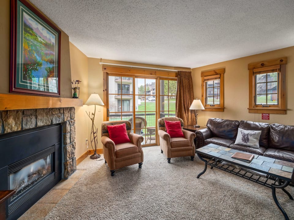 You will love the large open living room in this condo. There is a private balcony right through the sliding door.  - Fireplace, chairs, sliding glass door