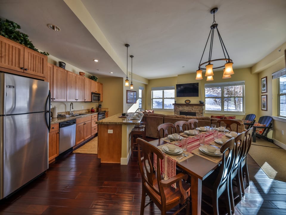 Spacious open-concept kitchen and dining area with wooden cabinets, stainless steel appliances, granite countertops, a large dining table