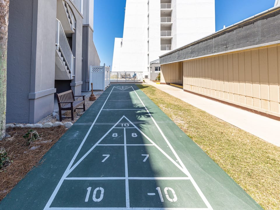 A shuffleboard court awaits your next friendly match, tucked beneath blue skies in this coastal community's shared outdoor space.