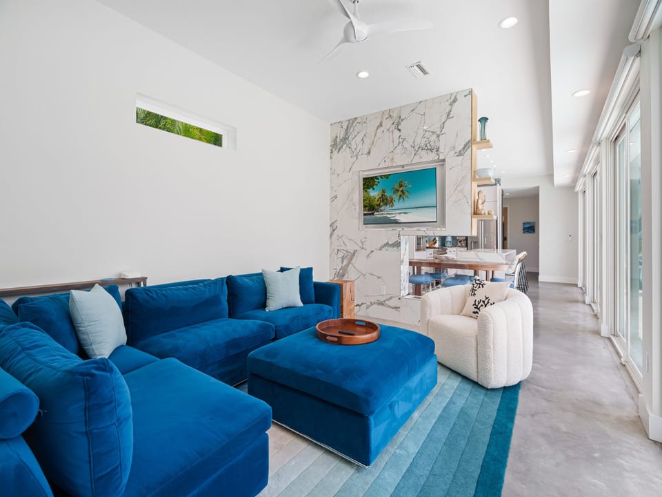 Sink into plush ocean-blue seating beneath soaring ceilings with elegant marble accents. Your open-concept haven flows seamlessly to coastal-inspired spaces, inviting relaxation and connection.