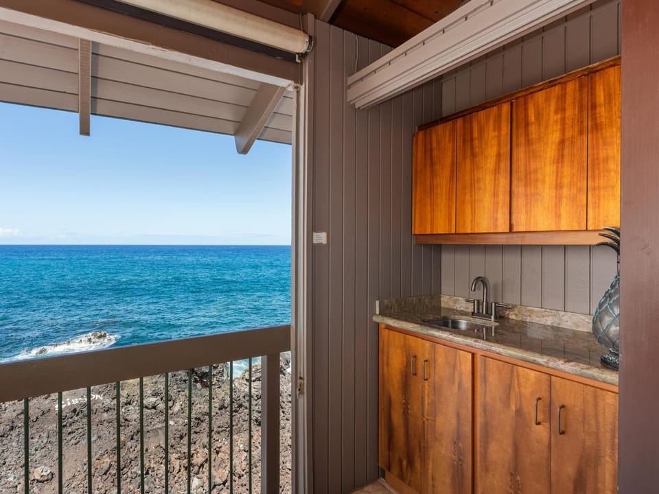 Open your kitchen to stunning turquoise waters and rocky coastline stretching to the horizon. This charming kitchenette brings warmth with rich wood cabinetry, while you prepare meals with the ocean as your backdrop.