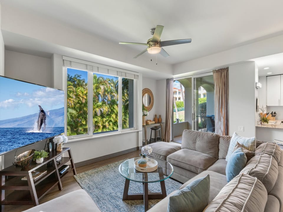 Step into your bright island retreat where soft ocean breezes and natural light fill the space through generous windows framing tropical palms. Sink into the plush sectional and unwind in your airy, breezy sanctuary.