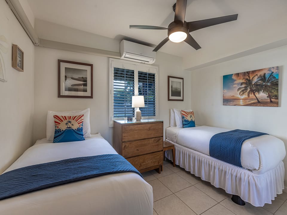 Rest peacefully in these twin beds with tropical decor, ceiling fan, and AC for your comfort.