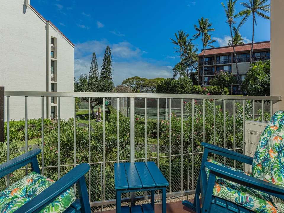 Relax on your private balcony with tropical garden views, where vibrant blue furniture and palm-patterned cushions create the perfect spot to unwind.