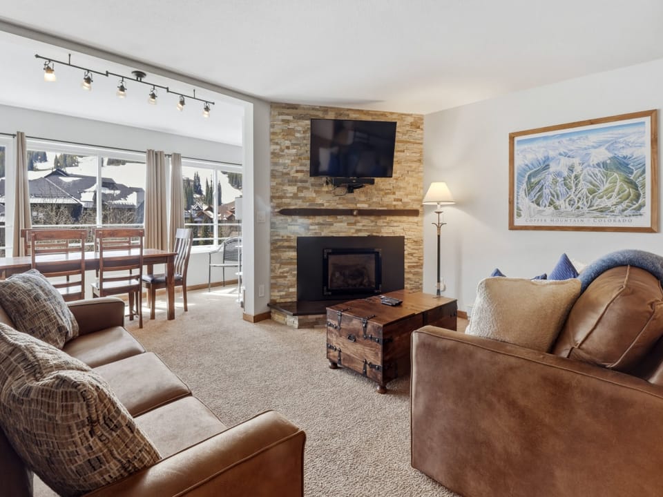 Unwind in your cozy living space with a crackling fireplace, comfortable leather seating, and mountain views from your private balcony.