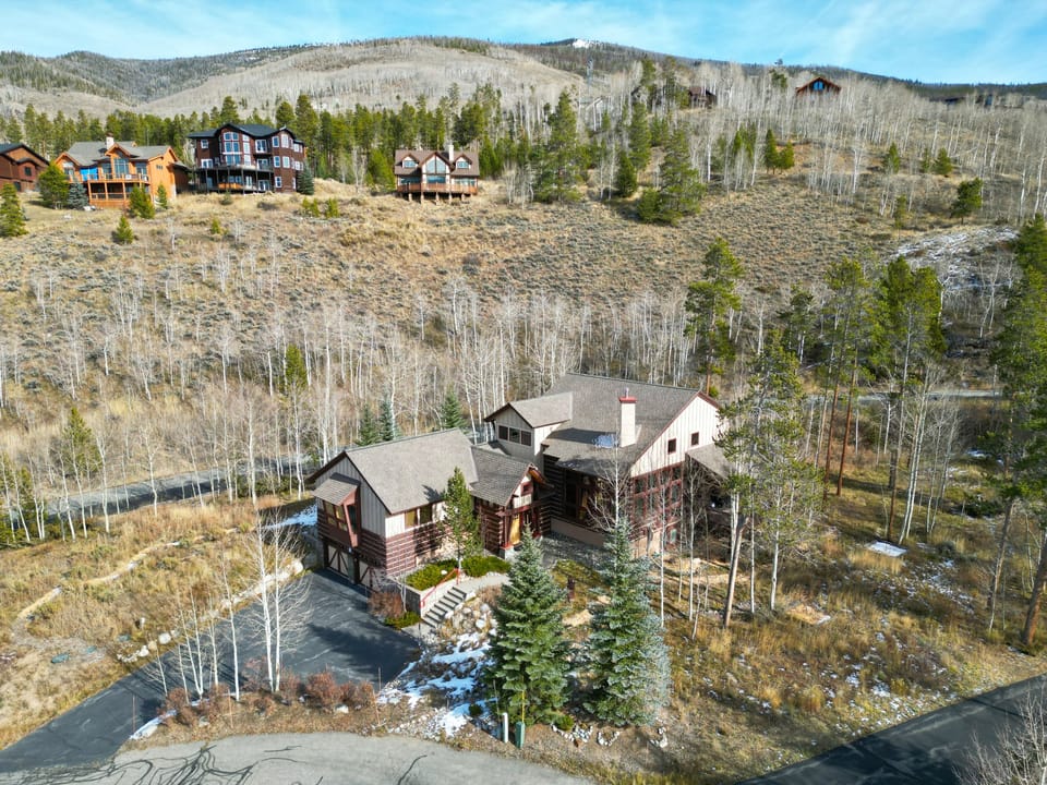 Aerial view of home, surrounded by wooded area with great mountain views.