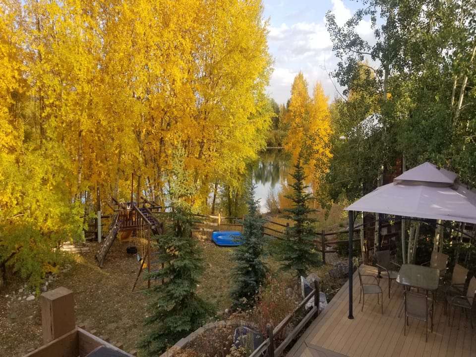 Beautiful backyard area features a playset, pond, and large private deck area.