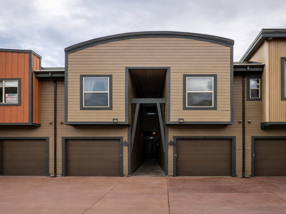 Modern townhome complex featuring contemporary architecture with varied siding colors and private garage access for each unit.