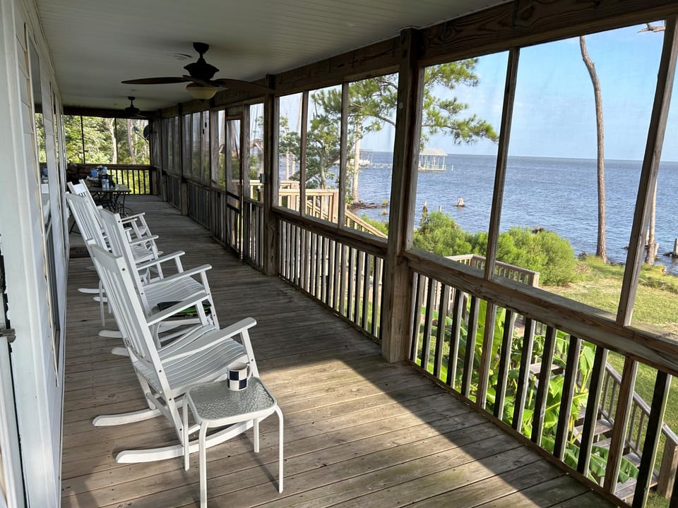 Relax on the screened porch with white rocking chairs and enjoy the serene bay view, perfect for unwinding with the family
