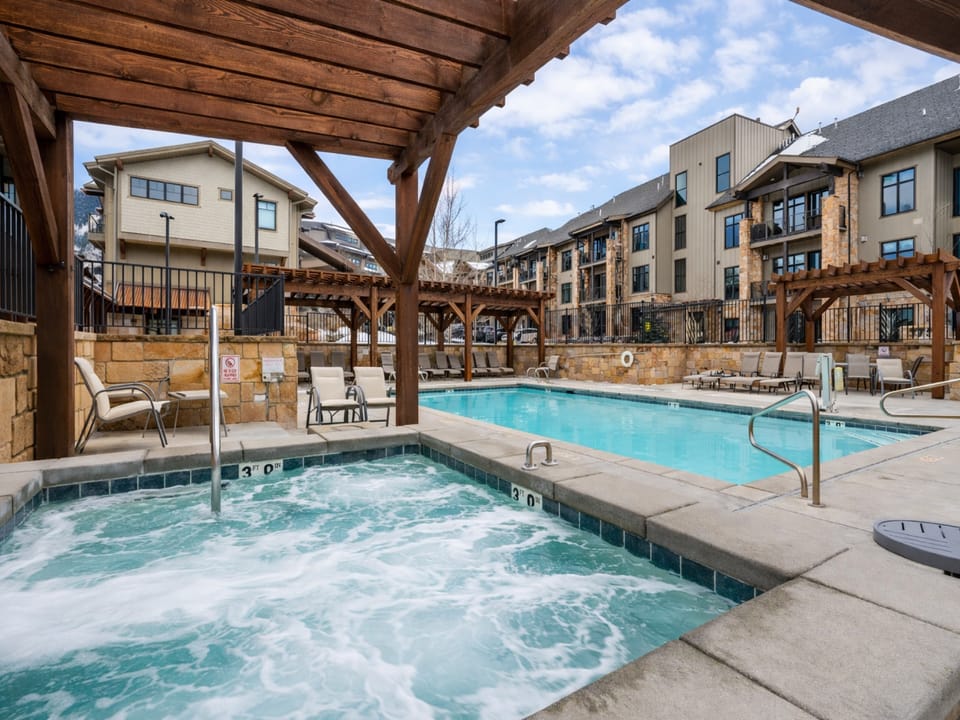 Soak in the luxurious outdoor hot tub or take a dip in the heated community pool. This resort-style amenity area features a wooden pergola and is surrounded by stunning mountain views.