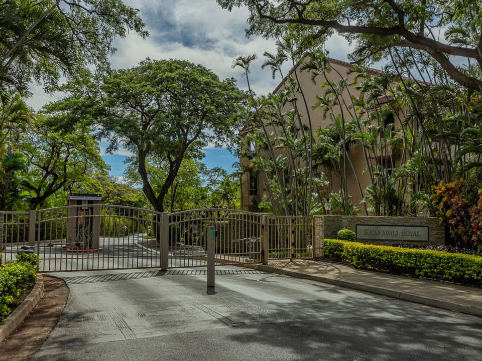 The gated entrance to Ka'anapali Royal, framed by lush tropical trees and manicured hedges.