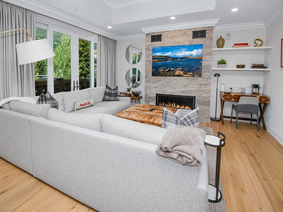 Sink into plush seating and feel the warmth of the fireplace as you unwind in this elegant living space, complete with a cozy workspace and views of lush greenery just beyond your door.
