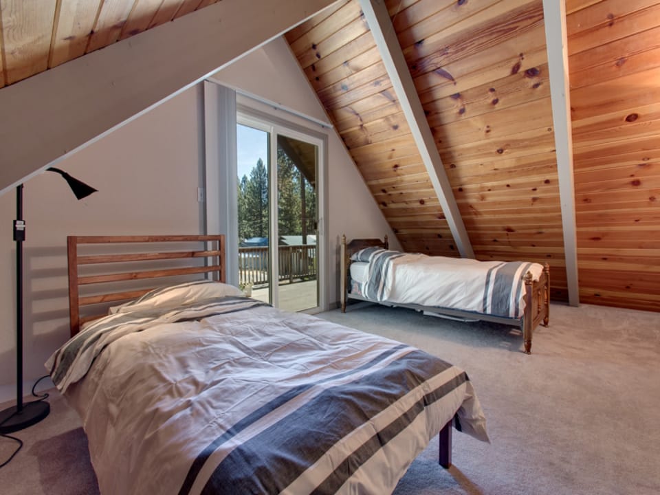 Twin beds in the upstairs loft, offering a cozy sleeping space with a charming sloped ceiling.