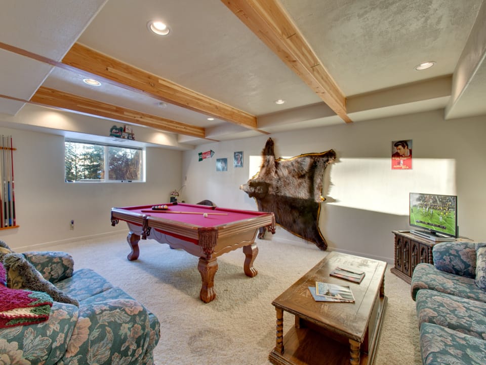 Game room with a pool table, cozy seating, and rustic mountain décor for endless entertainment.