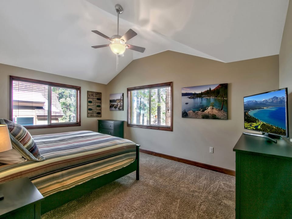 Spacious bedroom with a king bed, ceiling fan, and large windows