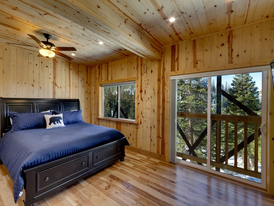 Inviting bedroom with wooden accents, offering views of the surrounding forest.
