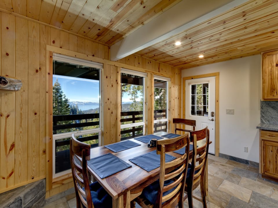 Charming dining area with wooden accents and panoramic views of the lake and forest.