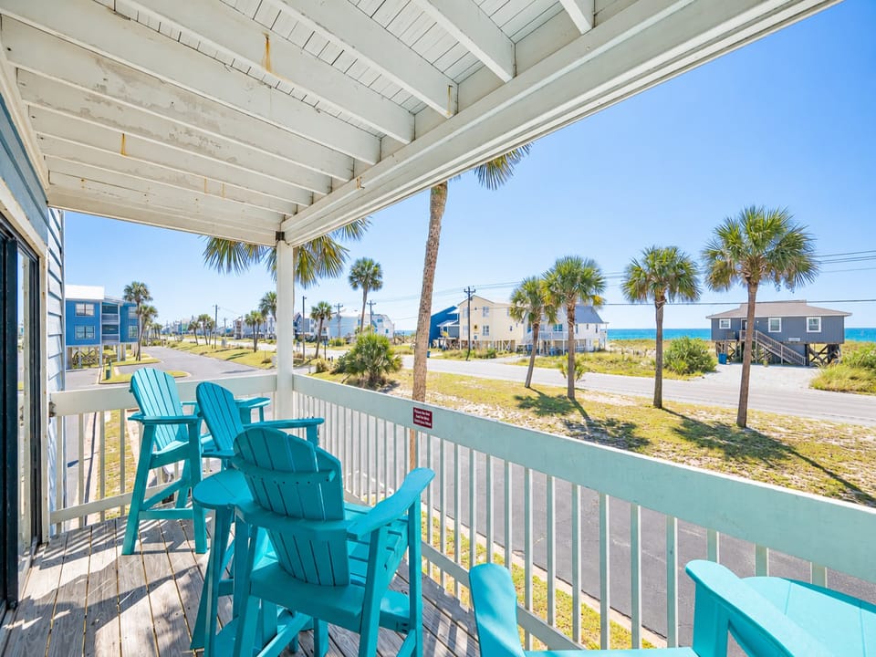 Enjoy a relaxing view from the turquoise chairs on the balcony, with palm trees framing the beach scene ahead