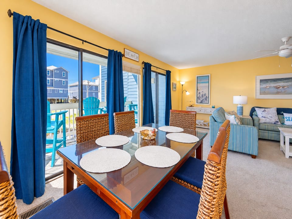 This inviting dining area features a glass-top table with chairs and offers a bright view through large windows