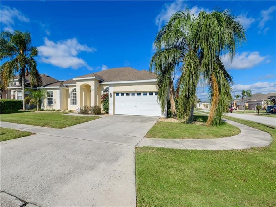 Beautiful front exterior with a double driveway and tropical landscaping.