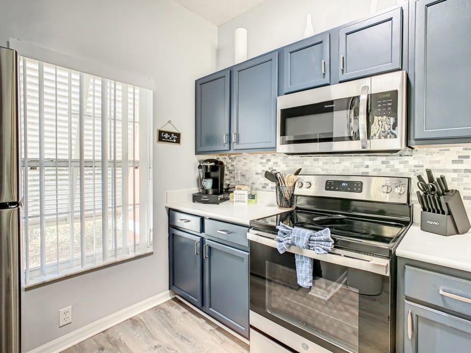 Modern kitchen with stainless steel appliances and vibrant blue cabinets for a sleek look.