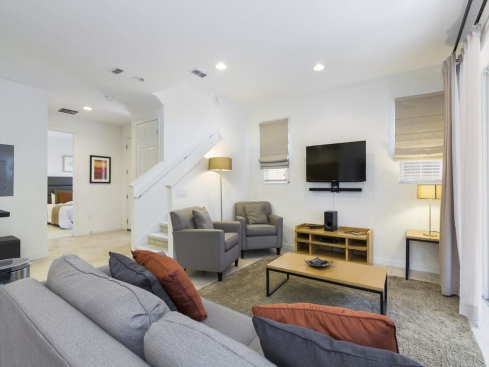 Stylish and bright open-plan living space with comfortable seating and a mounted TV.