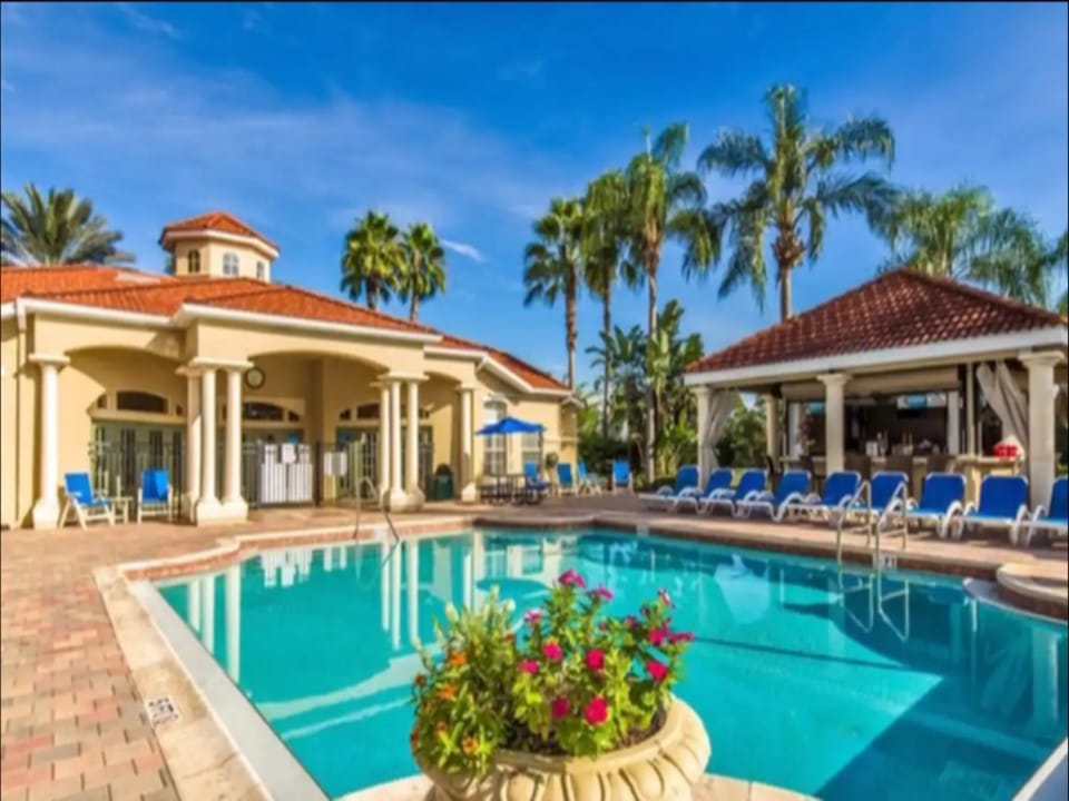 Resort-style pool surrounded by palm trees and ample lounge seating.