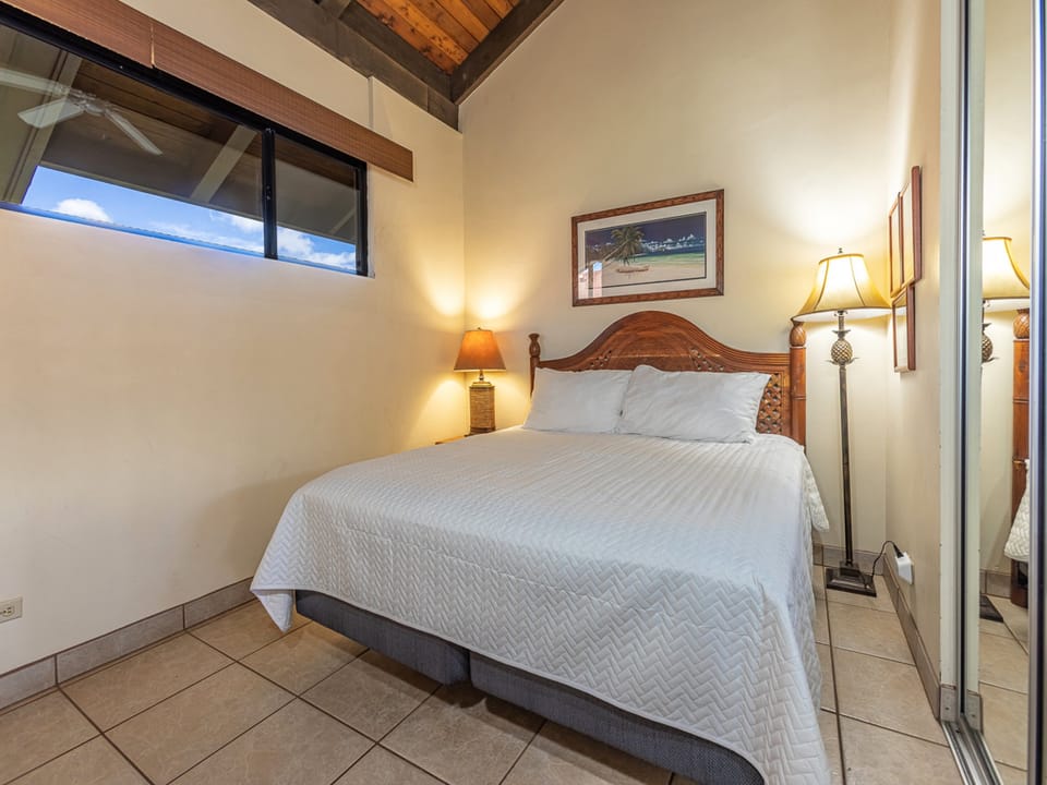 Your serene bedroom features warm lighting and a charming vaulted ceiling with exposed beams that create a cozy, island-inspired retreat.