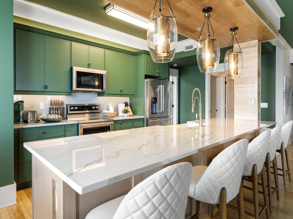 Your gourmet kitchen awaits with emerald cabinets, marble countertops, and stylish pendant lighting for memorable cooking experiences.
