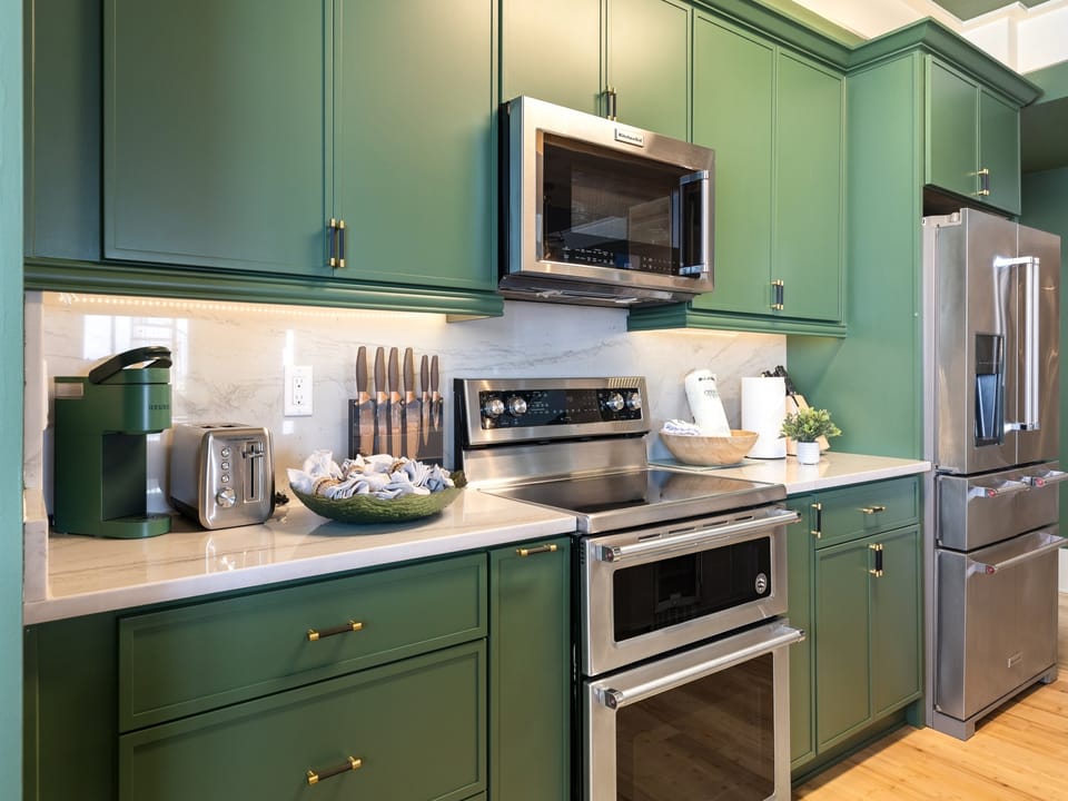 Cook memorable meals in this stunning sage green kitchen with premium stainless steel appliances and elegant quartz countertops.