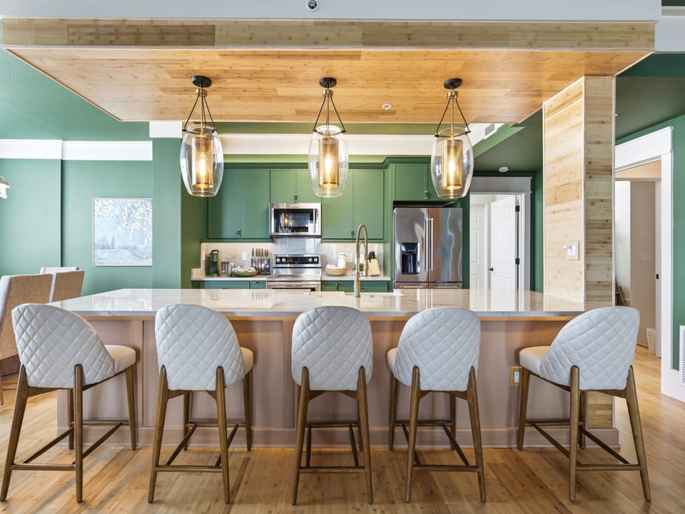 Gather around this stunning kitchen island with stylish bar seating, where warm wood meets refreshing green tones for memorable meal prep together.