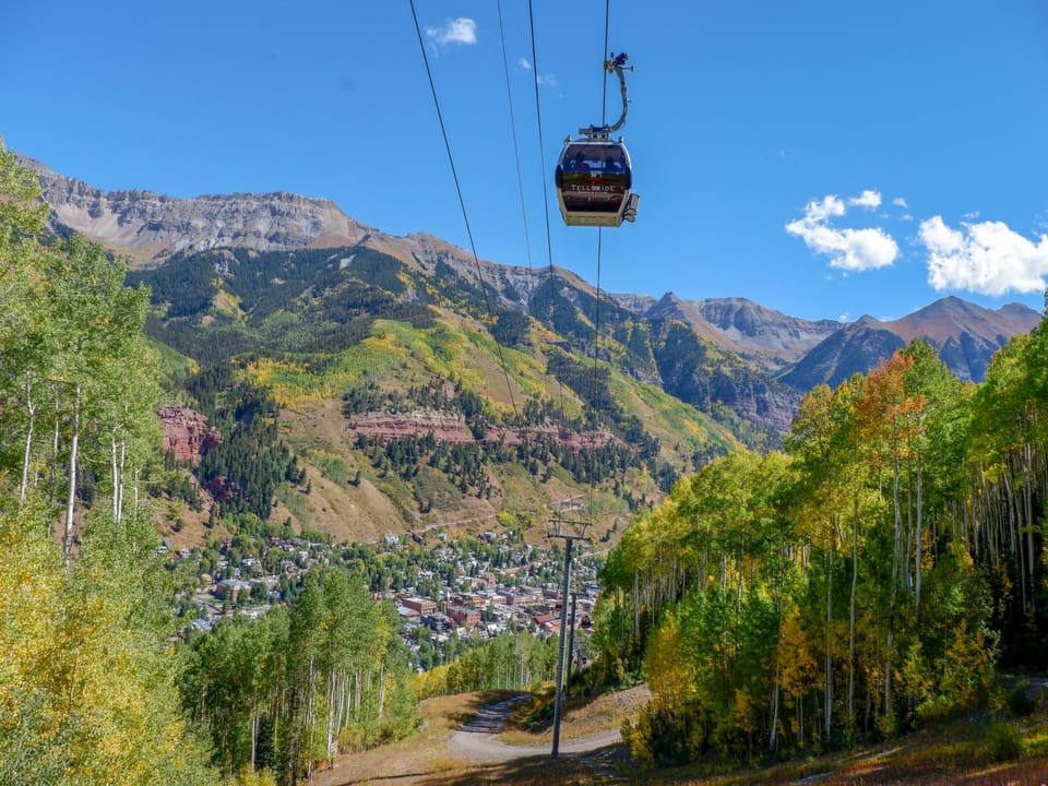 Mountain gondola offers scenic transportation above a charming alpine town nestled in dramatic peaks.