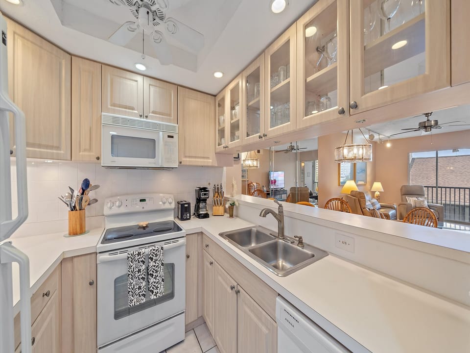 Kitchen fully equipped with coffee maker, appliances, cookware, utensils, and glassware.