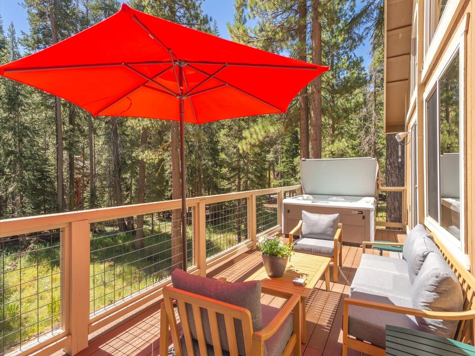 Your summer oasis awaits: The back deck offers stunning views of Tahoe Forest, complete with cozy lounge seating, a Weber barbecue, and a brand new hot tub.