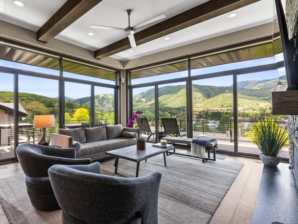 The living room has a wall of windows with views of Deer Valley Resort and Park City Mountain Resort including the Canyons.