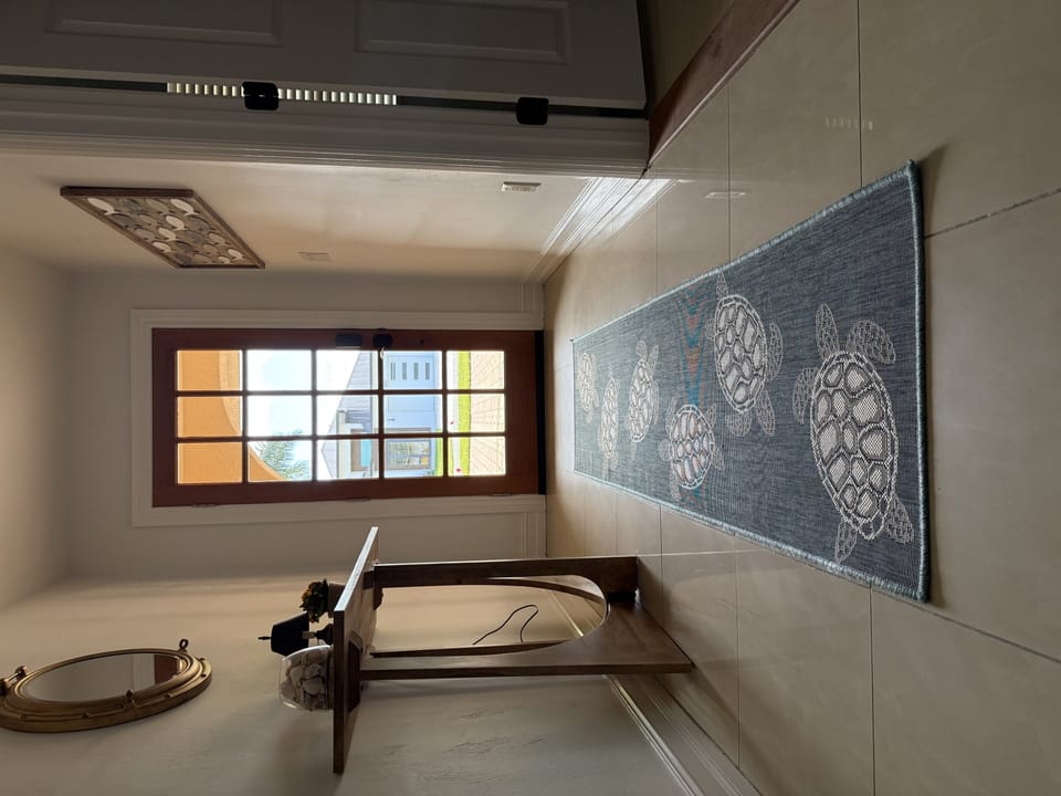 Unwind in your elegant bathroom featuring a mosaic turtle design, deep soaking tub, and natural light streaming through the window.