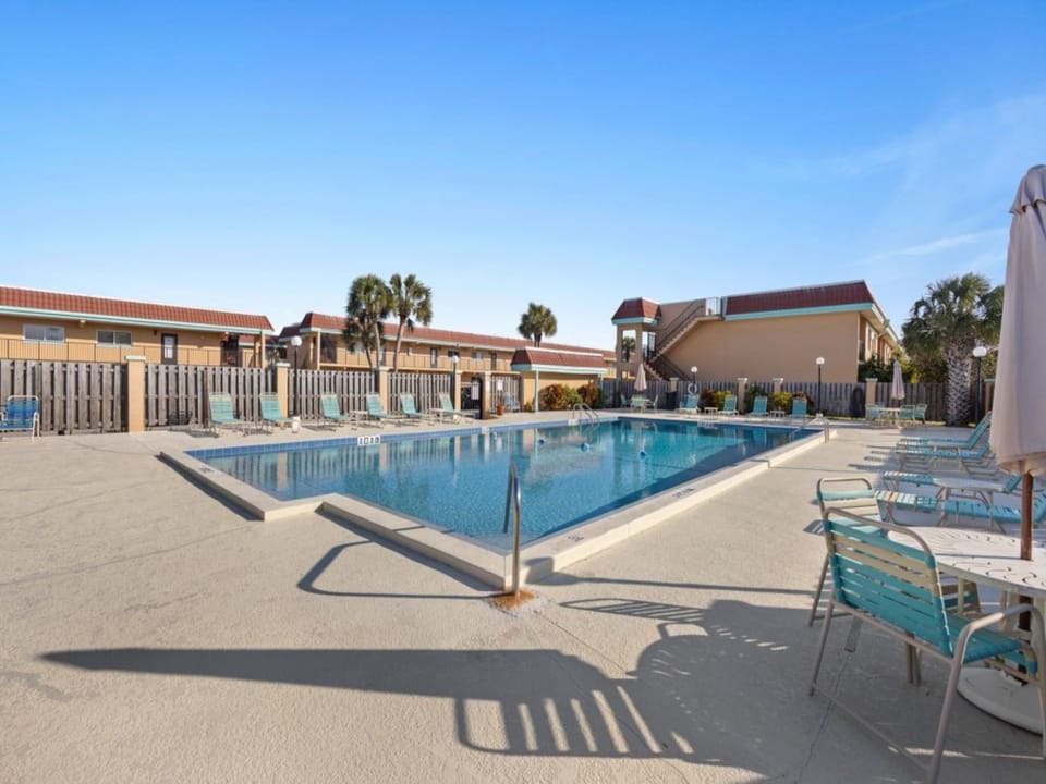 Sunny pool area with ample loungers and clear blue skies for a revitalizing swim.