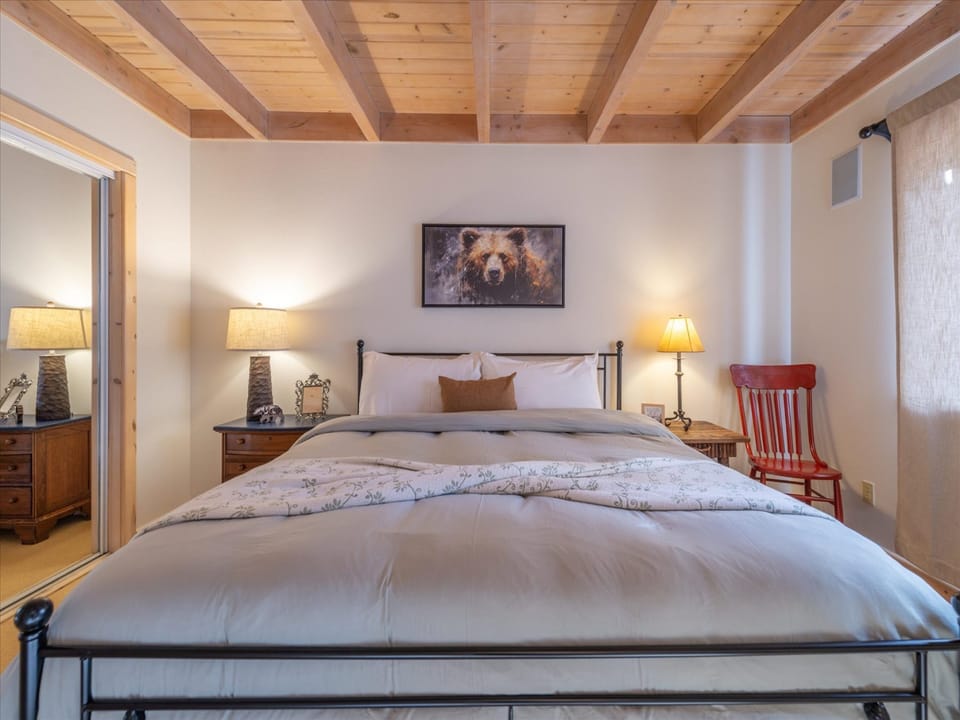 Drift off to sleep under exposed wooden beams that create a cozy alpine feel. Your comfortable bed awaits with crisp linens and warm ambient lighting from bedside lamps that cast a gentle glow.