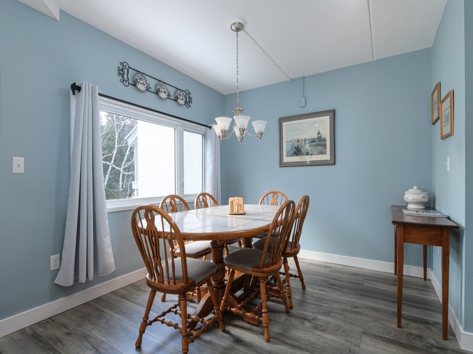 Gather around this charming dining space where warm wood meets soothing blue walls, creating the perfect atmosphere for your memorable meals together.