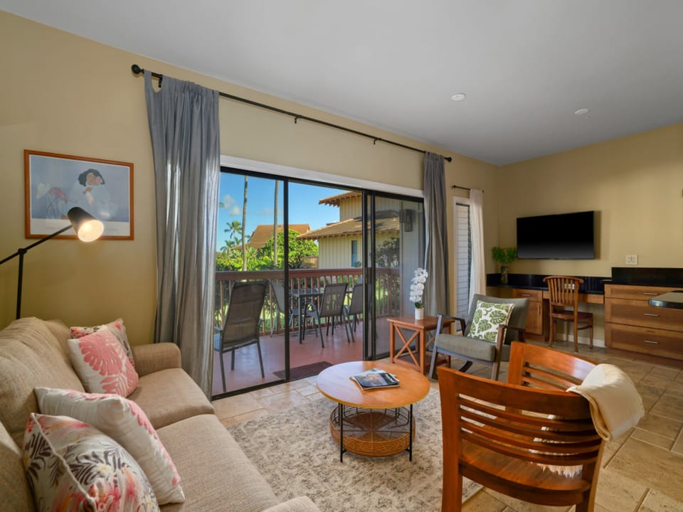 Your comfortable living space opens to a private balcony through sliding glass doors, featuring plush seating and warm wood accents.