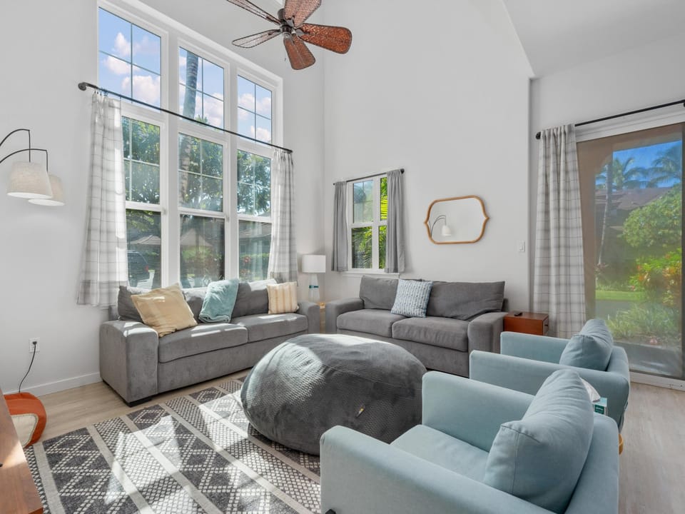 Sink into plush gray sofas and unwind in your bright, airy living space with natural light streaming through tall windows.