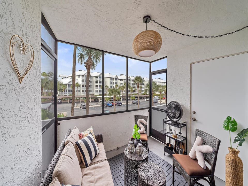 Relax in your bright, airy living space with panoramic windows that fill the room with natural light and showcase views of palm trees and the surrounding area.
