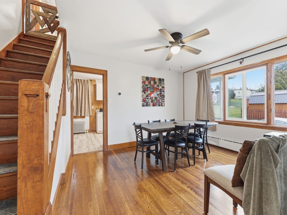 Built in the graceful mid-century era, this home features classic architectural touches and a clean, functional layout that feels both nostalgic and beautifully timeless. This stairway connects the upper and lower floors with a gate at the top for safety (baby-gate at bottom of stairs available upon request.) Bright and warmly lit, this room is perfectly suited for family meals. The unique art decor is designed to bring peace and calm to your dining experience.